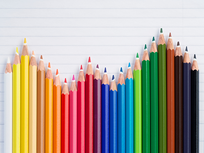 Colored pencils side-by-side in a rainbow fashion placed at different heights
