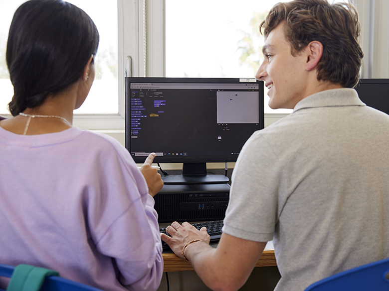 Two students collaborating. Image viewed as if standing behind them with the view of their computer screen
